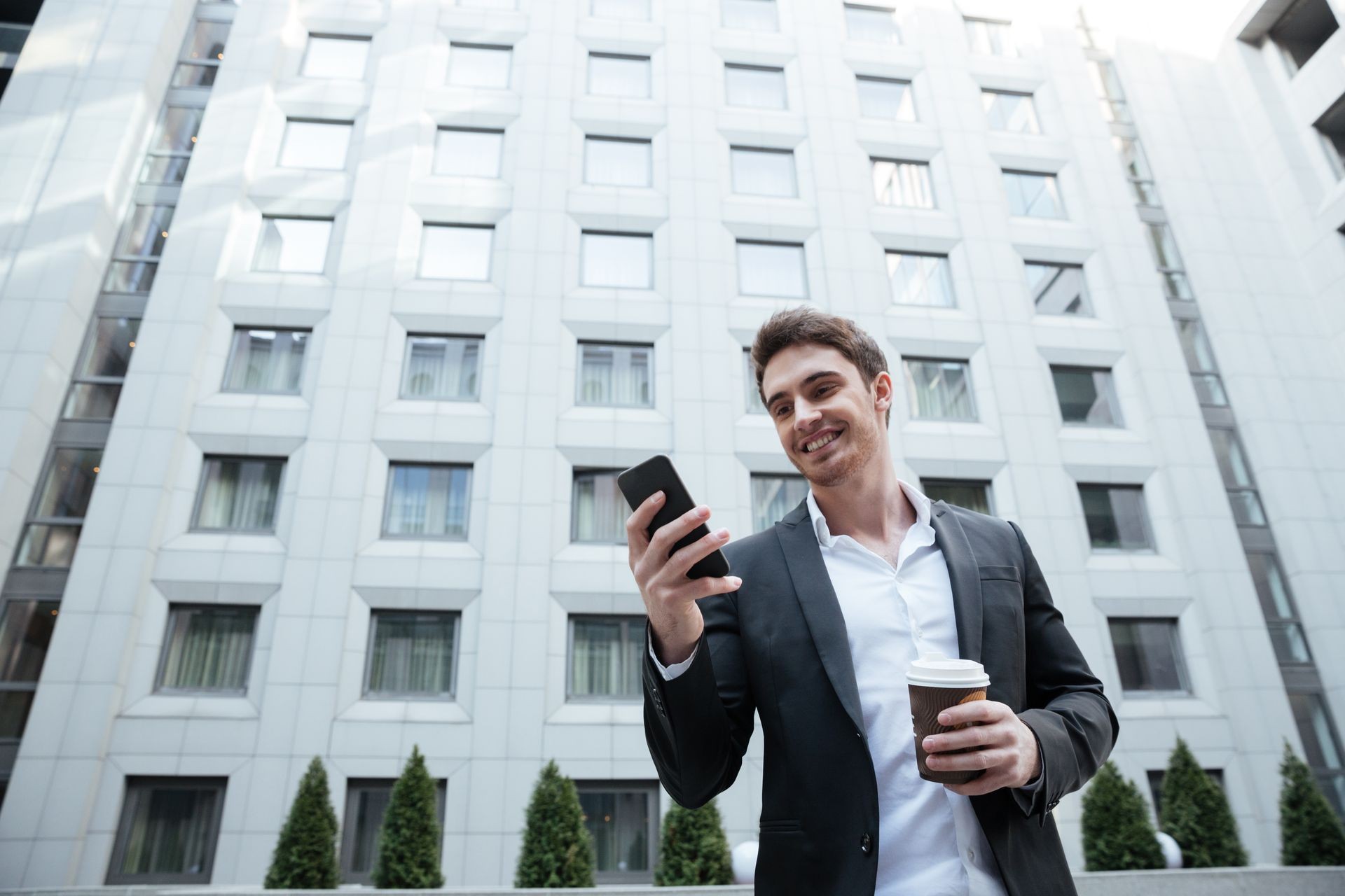 A split image showing an NRI investor smiling while looking at a smartphone screen, with the other side of the image showing a property manager in India conducting a virtual tour of the property for the investor.