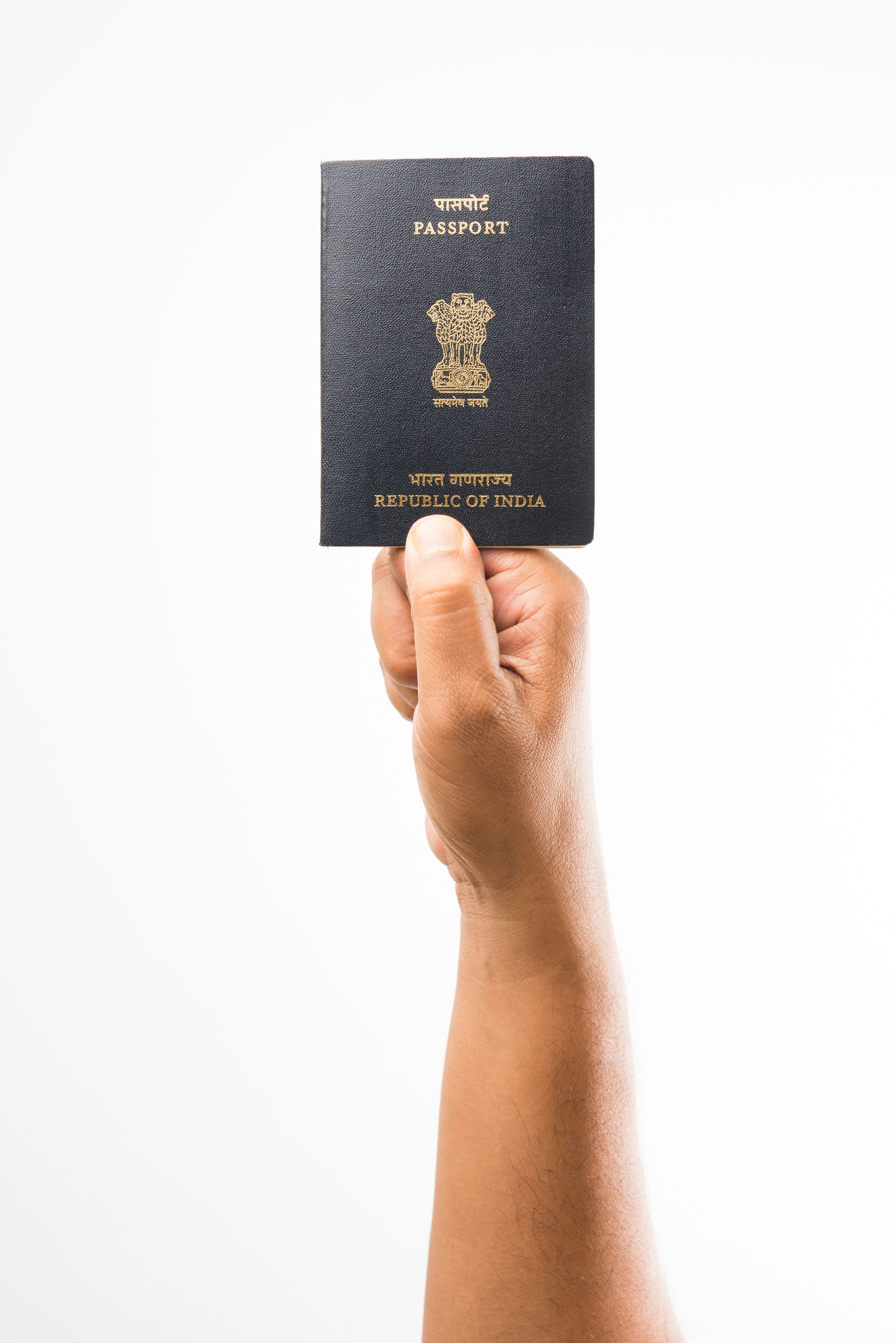 closeup picture of indian man holding indian passport over white background, selective focus